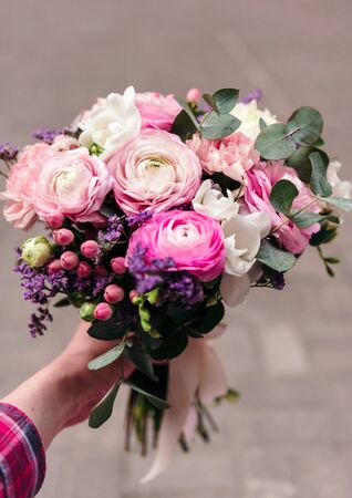 Delicate wedding bouquet of ranunculus flower, freesia and eucalyptus leaves in handの写真素材