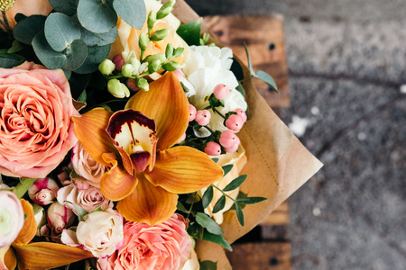 Colorful  bouquet of different fresh flowers against brick wall. Bunch of orchids, roses, freesia and eucalyptus leaves. Rustic flower backgroundの写真素材