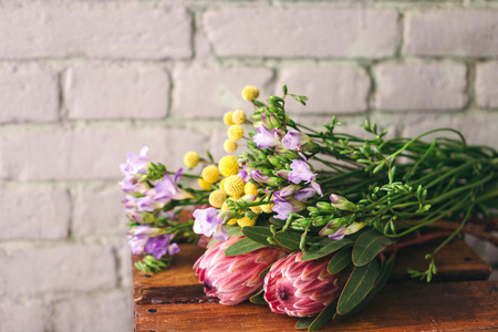 Florist working table with craspedia, freesia and protea flowers. Flowers delivery, creating orderの写真素材