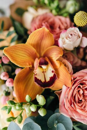 Colorful  bouquet of different fresh flowers against brick wall. Bunch of orchids, roses, freesia...
