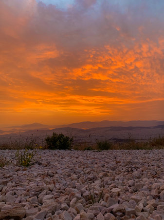 View of a golden sunset over the vast cityscape of distant Athens, and hazy hills of the Mediterranean coastline on the horizon, seen from a stony path atop the Hymettus mountain.の写真素材