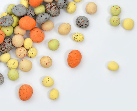 Easter egg chocolate candy background. Multi-colored chocolate decorative eggs on a white...