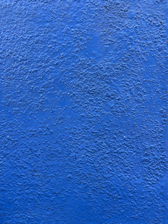 This image shows a surface painted blue. The surface has a distinct texture with small bumps or granules that give the impression of roughness. This is a wall or other hard surfaceの写真素材