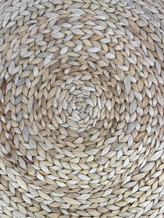 Close-up of round woven straw texture in natural beige tones. Rustic handmade wicker pattern with...