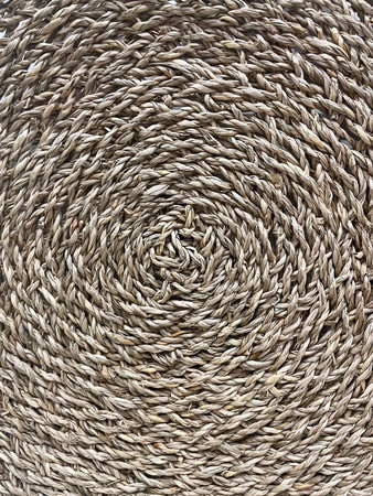 Close-up of a natural woven straw texture in circular pattern. Rustic eco-friendly handmade design,...