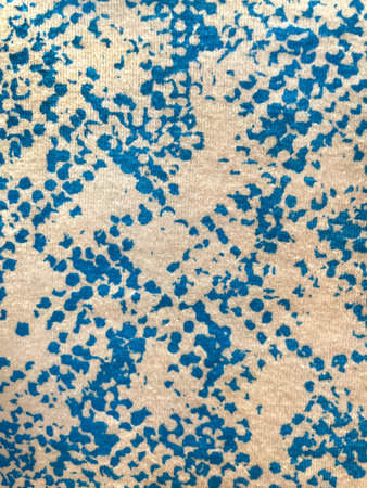 Abstract blue paint splatter pattern on beige fabric. Artistic textile texture with irregular spots and dots, modern background for fashion design, home decor, wallpapersの写真素材