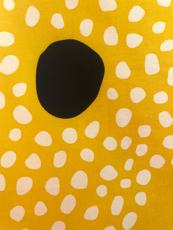 Abstract fabric pattern with bold black dot and scattered white spots on a bright yellow background. Modern textile design, playful and vibrant, ideal for fashion, decorの写真素材