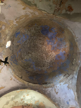 Ancient church ceiling with peeling plaster and faded fresco remnants. Old Byzantine architecture...