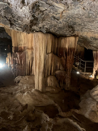 Natural cave formations with impressive stalactites and stalagmites, showing layered textures and...