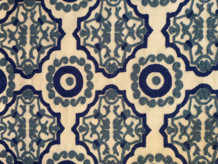 Close-up of embroidered fabric with intricate blue geometric and floral patterns on a beige background. Traditional Mediterranean textile design with ornamental motifs, handmadeの写真素材