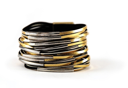 A wide shiny gold leather bracelet with layered strips - trendy chic female accessory isolated on white background, a sign of confidence and classの写真素材