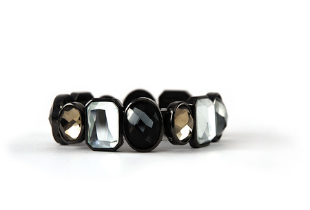 Close-up of trendy shiny sparkling women's bracelet, combined of black, gold and translucent faceted stones, the object isolated on a white backgroundの写真素材