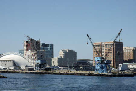 Insdustrial cranes for boat on Boston's pier with skyline on the back,  Boston, Mass USA