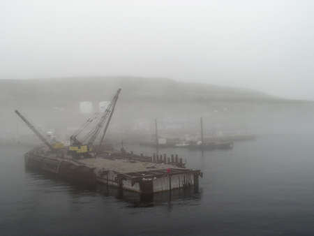 dock construction workers in the mist on the St Laurence Gulf, Newfoundland, Canadaの写真素材