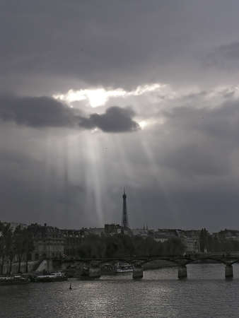 Clouds over Paris bridge and and Eiffel tower from La Seine on a cloudy sundown