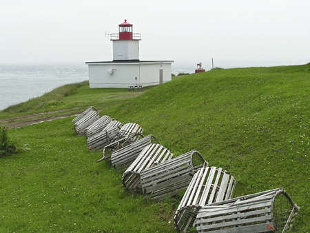 lobster traps sitting on the grass  near a lighthouse in New Brunswick harbor, Canadaの写真素材