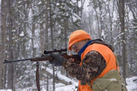 Senior hunter aiming a deer in his sight under the snow,Quebec, Canadaの写真素材
