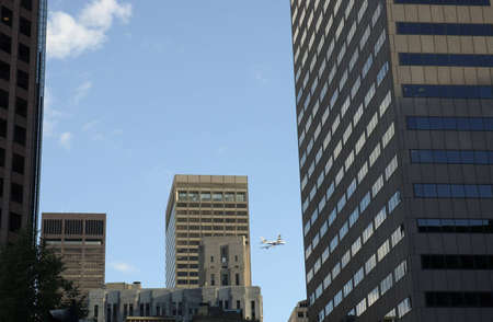 passengers airplane behind skylines in cityの写真素材