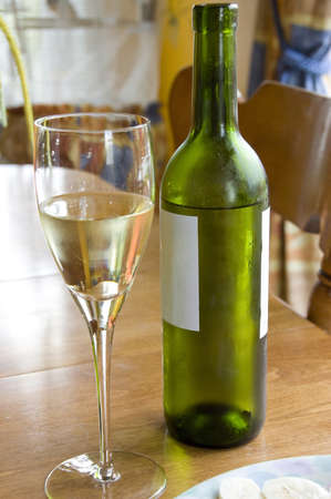 Glass of white wine and a frosty bottle of white wine on a tableの写真素材