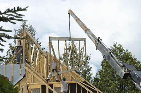 QUEBEC, CANADA - JULY 4TH ; workers framing a roof of a new house  with the help of a construction crane, Quebec, Canada, 4th July 2006のeditorial素材