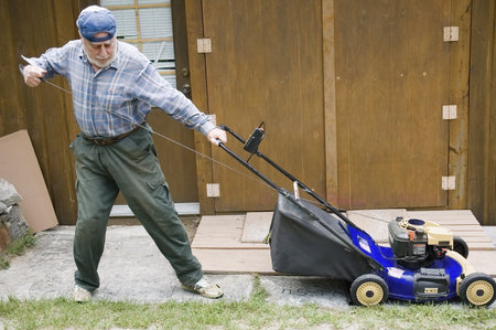 Quebec, Canada - July 2th, 2006 :  Senior starting manually a lawn mower, focus on the tool - motion pictureのeditorial素材
