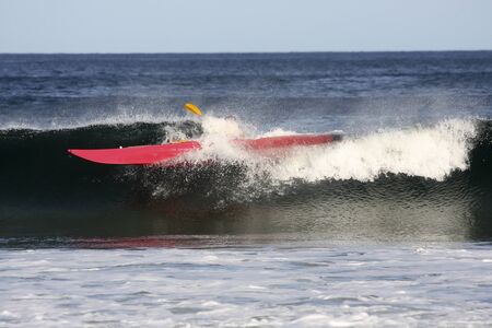 Kayak surfer paddling on the crest of a big wave in rough sea of Nova Scotia coast, Canada