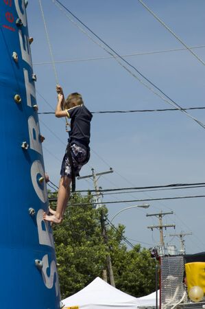 MONT LAURIER, QUEBEC, CANADA - JULY 13, 2006  :young boy training on an outdoor climbing tower at a fair show held in street of rural country of Quebec, Canada on July 13, 2006のeditorial素材