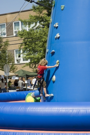 MONT LAURIER, QUEBEC, CANADA - JULY 13, 2006 : Little blondie girl training on an outdoor climbing tower at a fair show held in street of rural country of Quebec, Canadaのeditorial素材