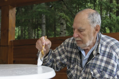 aged senior man with expressive face painting carefully  a garden  tableの写真素材