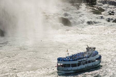 people taking a ride on a cruise boat  nearby the Niagara falls in Autumn, Ontario, Canadaの写真素材