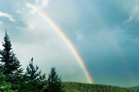 blue sky and double rainbow over mountains in Quebec country, Canadaの写真素材