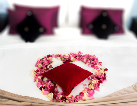 Heart of rose petals on a romantic bedの写真素材
