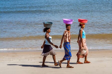 Malagasy women carrying basins on their heads walking on the Amborovy beach near Mahajanga (Majunga), Madagascar on august 27, 2016.のeditorial素材