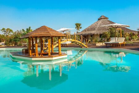 luxury swimming pool with a wooden bridge and central barの写真素材