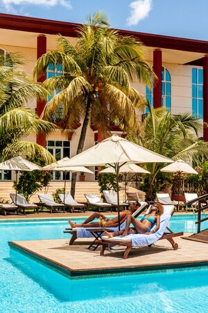 Two women sunbathing on sunbeds by the poolの写真素材