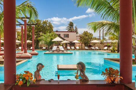 Two beautiful young Malagasy women drinking cocktails in the swimming pool barの写真素材