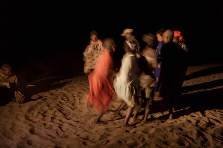 Malagasy villagers and their makeshift musical instruments dancing near the wood fire at dusk on the banks of Tsiribihina river, Madagascarのeditorial素材
