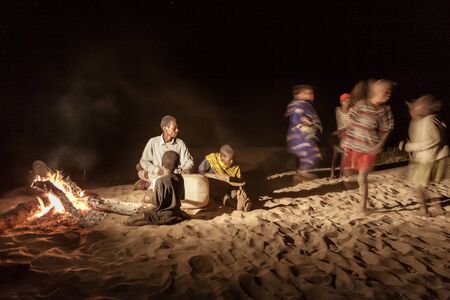 Malagasy villagers and their makeshift musical instruments dancing near the wood fire at dusk on the banks of Tsiribihina river, Madagascarのeditorial素材