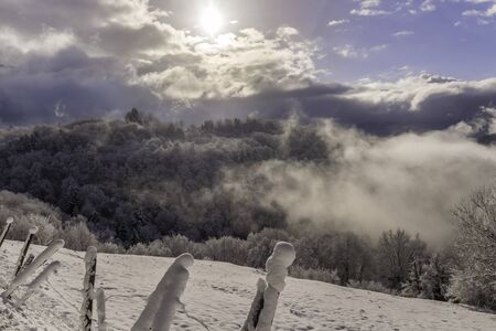 Snowy landscape with sun and clouds in the mountains near Grenoble in the French Alpsの写真素材