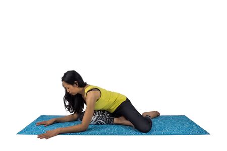A woman yoga teacher in saithalyasana posture isolated on white backgroundの写真素材