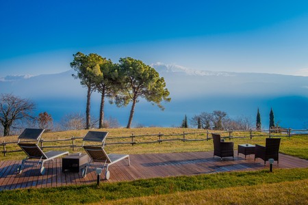 garden furnished with tables, chairs and deckchairs with lake viewの写真素材
