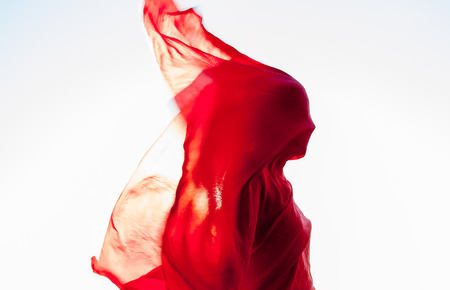 woman wrapped in a red scarf in the windの写真素材