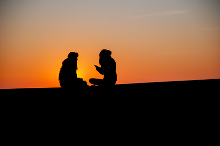 confidences between two teenagers at sunset.の写真素材