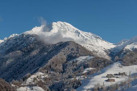 sun illuminating mountain village after snowfallの写真素材