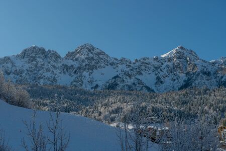 sun illuminating mountain village after snowfallの写真素材
