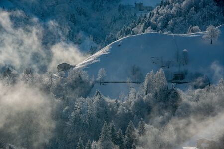 sun illuminating mountain village after snowfallの写真素材