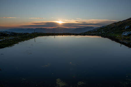 mountain pond reflecting the sunsetの写真素材