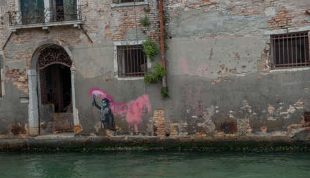 Venice Italy 18 July 2020: Murals by Banksy in Venice inspired by the theme of immigration, as it depicts a child wearing a life jacket and holding a fuchsia signal rocketの写真素材