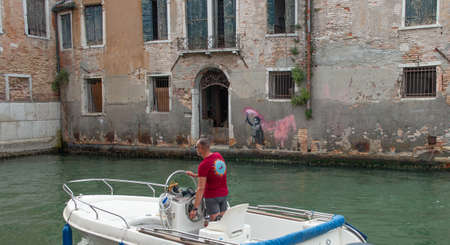 Venice Italy 18 July 2020: Murals by Banksy in Venice inspired by the theme of immigration, as it depicts a child wearing a life jacket and holding a fuchsia signal rocketの写真素材