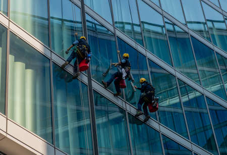 milan italy march 29 2021: skilled glass cleaners who lower themselves with slings from aboveのeditorial素材